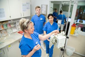 Pflegepersonal in blauen Kitteln an einem medizinischen Gerät